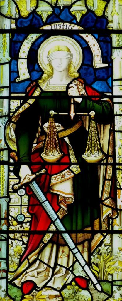 Vitral representando a la figura de Justicia, con una balanza y una espada, simbolizando los principios de la Enseñanza Social Católica.